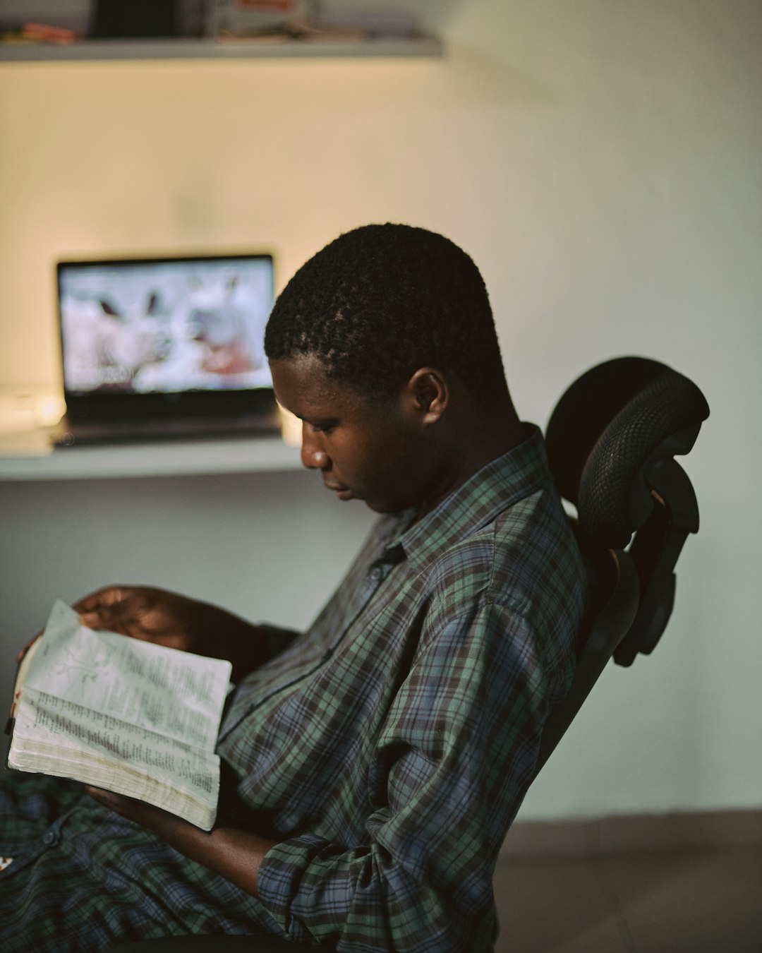 Closeup of a creative African man reading a bible with his workspace blurred in the background